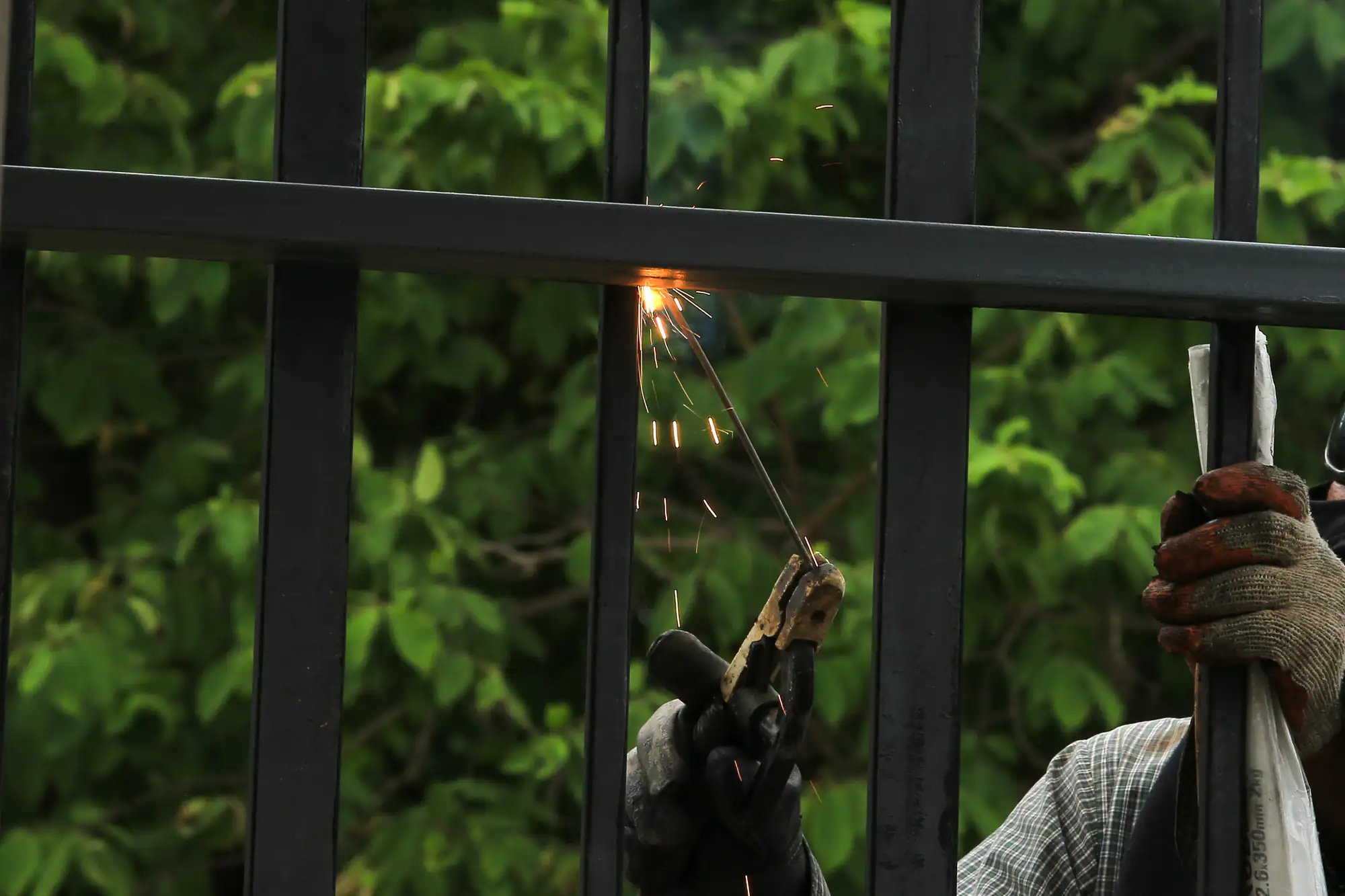 A person welding a metal fence with sparks flying for a NY fence contractor in Suffolk County.